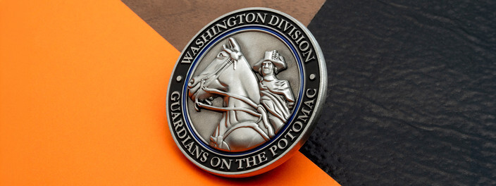 Antique silver coin with a sculpted horse and rider inside a black and blue ring, on orange paper and black leather