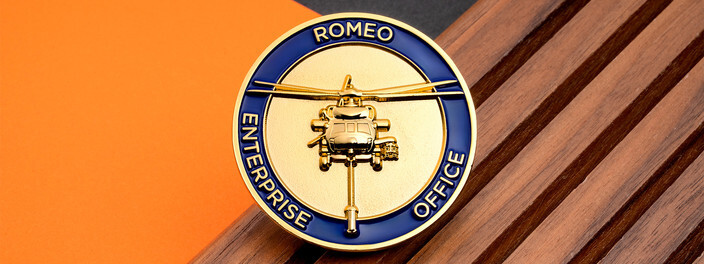 Gold coin with a raised helicopter inside a blue ring reading Romeo Enterprise Office