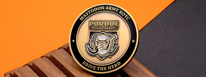 Antique gold Army ROTC coin with a mastodon head mascot, ringed by Drive the Herd