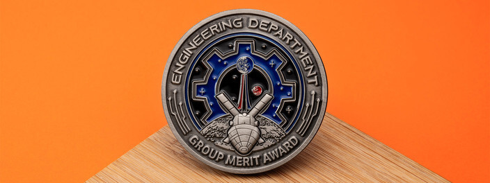 Antique silver engineering department group merit award coin with a gear and a lunar lander, on bamboo and orange paper