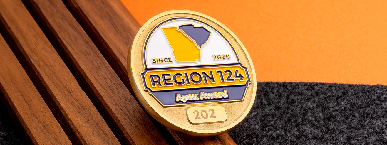 Gold Region 124 Apex Award coin with a map of Georgia and South Carolina, on dark wood and orange paper
