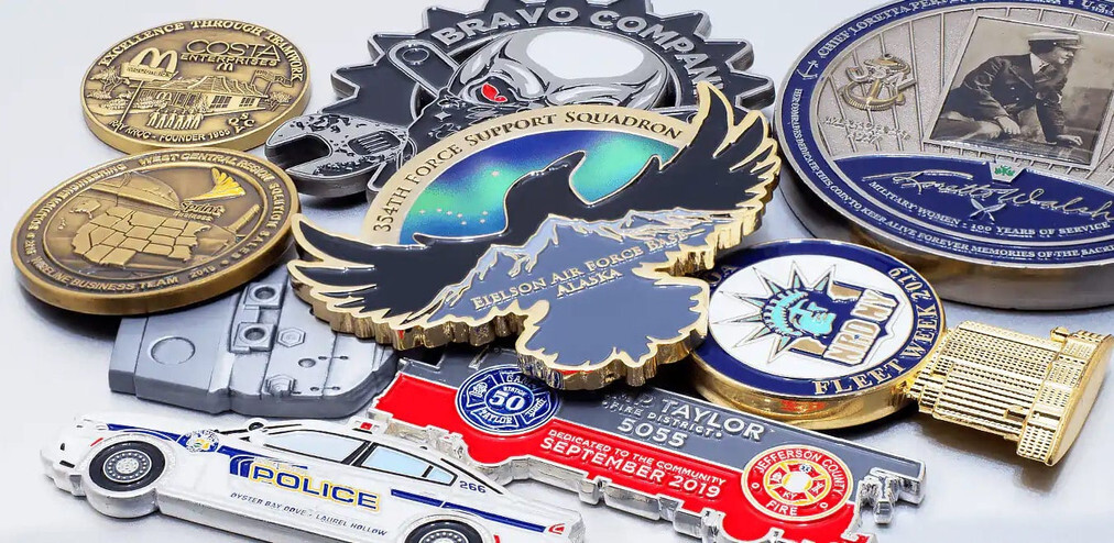 Pile of gold, silver and enamel coins in shapes like an eagle, a police car and a fire truck, on white