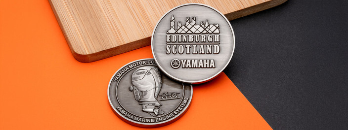 Two antique silver coins, one with an Edinburgh skyline and one with an outboard boat motor