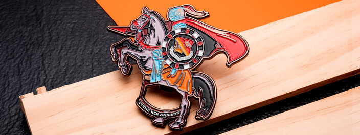 Coin cut in the shape of a knight with a red cape on a rearing gray horse, on light wood