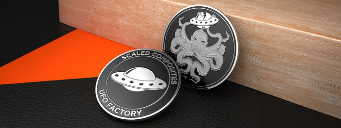Two black and silver coins, one with a flying saucer and one with an octopus holding a saucer