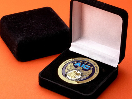 AIC gold and blue challenge coin in an open black velvet presentation box