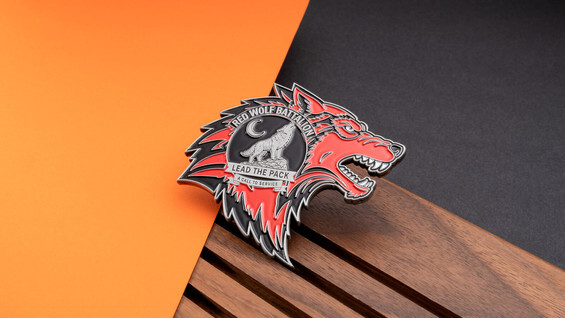 Wolf-head shaped coin in red and black enamel with a howling wolf, a crescent moon, and the words Lead the Pack