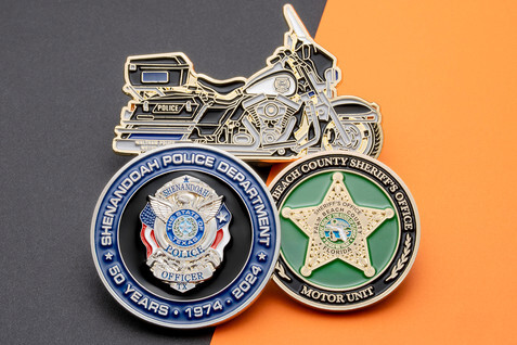Three police coins of different sizes and shapes, including one shaped like a motorcycle