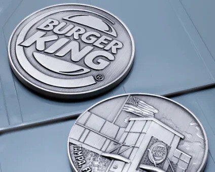 Two silver die struck coins with no enamel, one with a raised logo and one with a struck cityscape