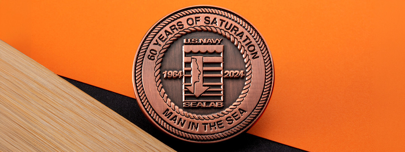Antique copper Navy SEALAB coin marking 60 years of saturation diving, 1964 to 2024, on orange paper and wood