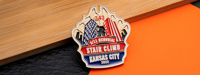 Red, white and blue 9/11 memorial stair climb coin cut to a city skyline, on wood and orange paper