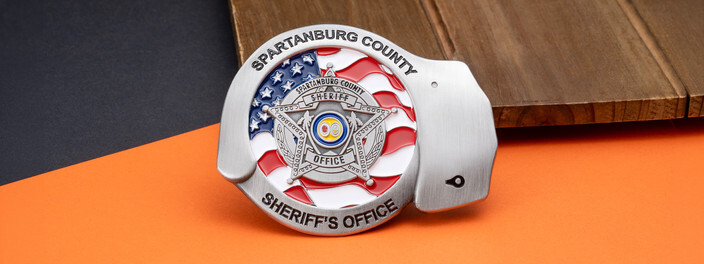 Silver handcuff shaped sheriff's office coin with a star badge over a waving American flag