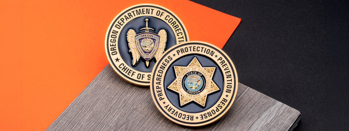 Two gold corrections department coins, one with wings and a sword, one with a seven point star