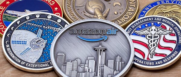 Overlapping enamel challenge coins with a satellite, a city skyline and a caduceus, on a wooden table
