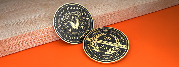Two black and gold university coins, one with a laurel framed V and one for a mechanical engineering class