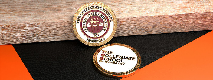 Two gold edged school coins, one with a university seal of three torches and one with a red and black logo