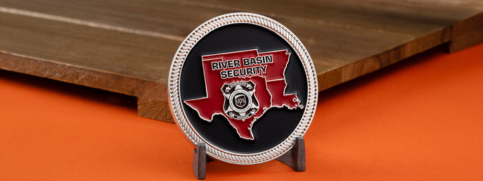 Silver rope edge River Basin Security coin with a red regional map and a badge, standing on a small stand