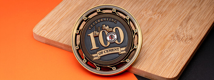 Antique gold centennial spinner coin for a cement company with an open work outer ring, on bamboo