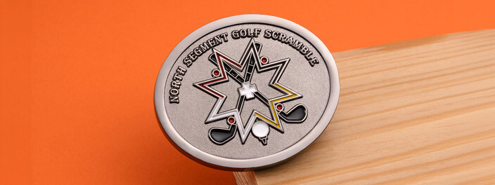 Silver golf scramble coin with a star outline, crossed clubs and a ball on a tee